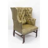 Georgian style leather button upholstered wing armchair, of broad proportions, raised on square inte