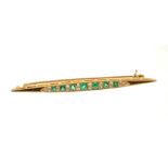 Edwardian emerald and diamond bar brooch with seven graduated mixed cut emeralds interspaced by old