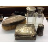 Two silver topped glass bottles, silver backed hairbrush, silver cigarette box and white metal peppe