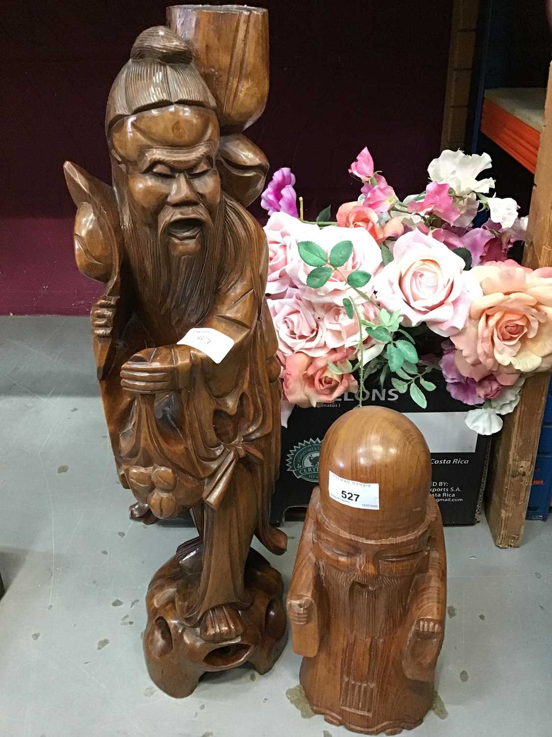 Two oriental carved wooden figures and artificial roses