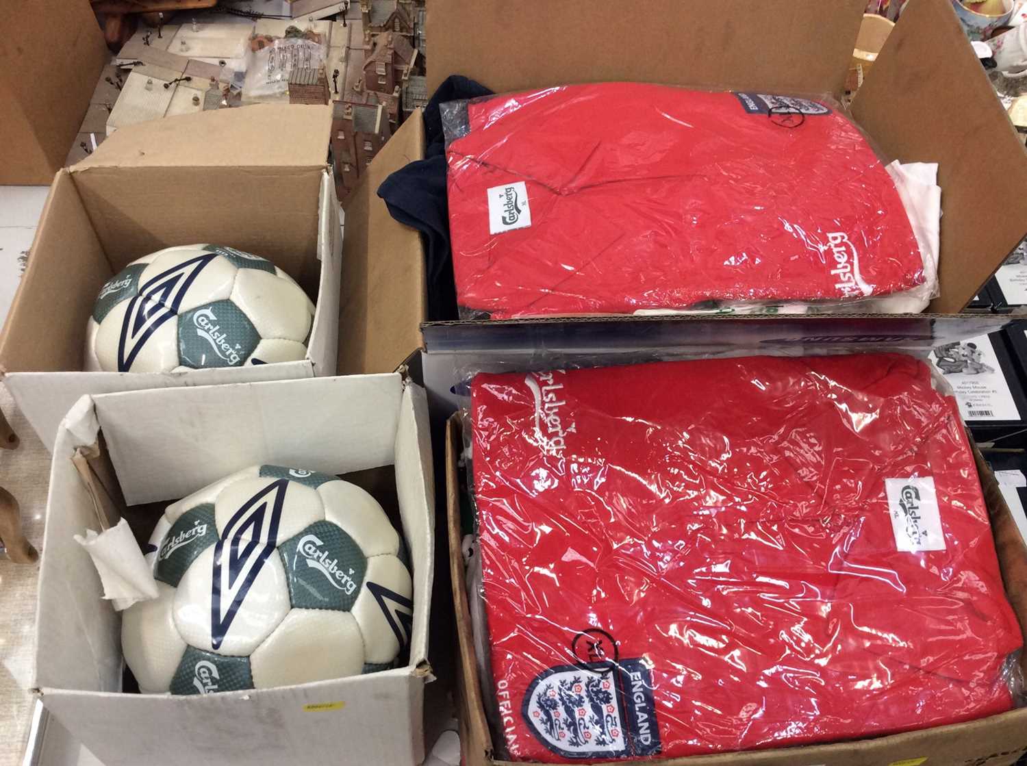 Two boxes England football polo tops, other sports T-shirt’s and two Carlsberg footballs