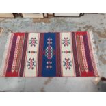Kelim rug with blue and white decoration together with another eastern rug on cream and blue ground
