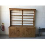 Antique pine two height dresser, with open shelves above with three panelled doors below, 215cm long