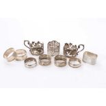 Eight assorted silver napkin rings, together with a pair of silver cup holders (Various dates and ma