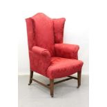 19th century wing armchair on mahogany and brass legs, upholstered in red silk fabric