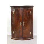 George III mahogany bowfront hanging corner cupboard with two doors enclosing painted shelves 103 cm