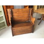 1930's oak monks bench with rising seat compartment and shaped arms H102.5cm W106.5cm D40cm