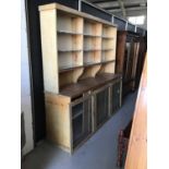 Large pine kitchen dresser with fixed shelves above behind three glass sliding doors and two sliding