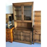Ercol elm two height bookcase with two glazed doors above enclosing two adjustable shelves, recess t