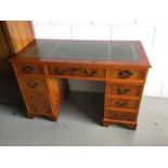 Reproduction yew wood twin pedestal desk with green leather top and an arrangement of eight drawers