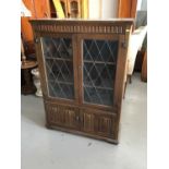 Old charm style bookcase enclosed by two leaded glazed and linen fold panelled doors