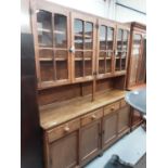 Large oak two height dresser with four glazed doors above, recess, four drawers and four sliding doo