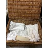 Wicker hamper containing various textiles, table linens and blankets