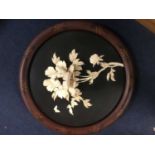 Japanese carved bone and lacquered circular plaque, in high relief with Chrysanthemum and butterfly
