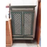 Green painted cupboard with shelved interior and two lattice work doors, two drawers below on square