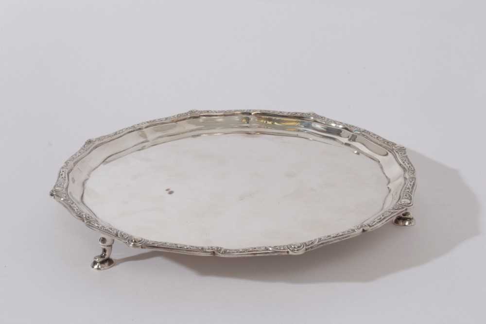 Contemporary silver waiter with pie crust edge and decorative border, raised on three hoof feet, (Bi