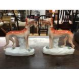 Pair Victorian Staffordshire figures of greyhounds, both with rabbits in their mouths, on oval gilt-
