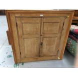 19th century stripped pine hanging corner cupboard with two panelled doors enclosing shaped shelves