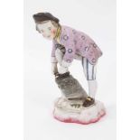 19th century French faience figure of a boy tying his shoelaces, wearing tricorn hat, lilac floral j