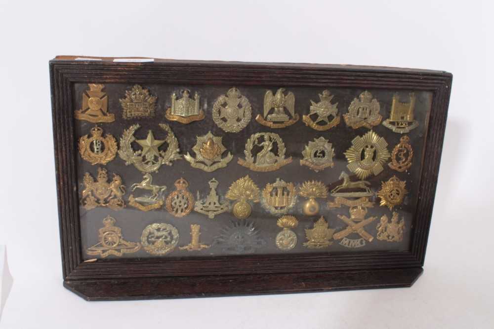 Group of First World War Military cap badges mounted in a glazed frame