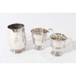 George V silver christening mug of tapered form with central reeded band, with scroll handle, on a c