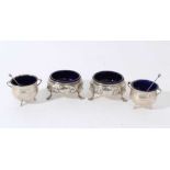 Pair of George III silver salt cellars of cauldron from with embossed floral decoration, and blue gl