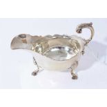 Late Victorian silver sauce boat of conventional form with scroll handle, raised on three hoof feet,