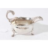 George II silver sauce boat of conventional form with engraved armorial, scroll handle, raised on th