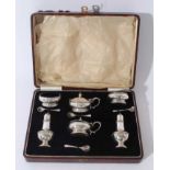 George V silver six piece cruet set comprising two mustard pots of cauldron form with blue glass lin