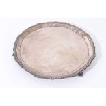 George VI silver salver with pie crust edge and gadrooned border, raised on three claw and ball feet