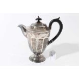 George V silver hot water jug of tapered form with faceted decoration, ebony finial and loop handle,