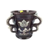 Castle Hedingham pottery four handled loving cup with applied 1650 and floral decoration on brown gr