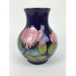 Moorcroft pottery vase decorated in the Magnolia pattern on blue ground, impressed marks and green p