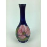 Moorcroft pottery slender neck vase decorated in the Magnolia pattern on blue ground, impressed mark