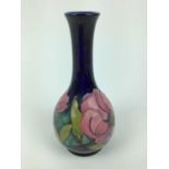 Moorcroft pottery slender neck vase decorated in the Magnolia pattern on blue ground, green painted