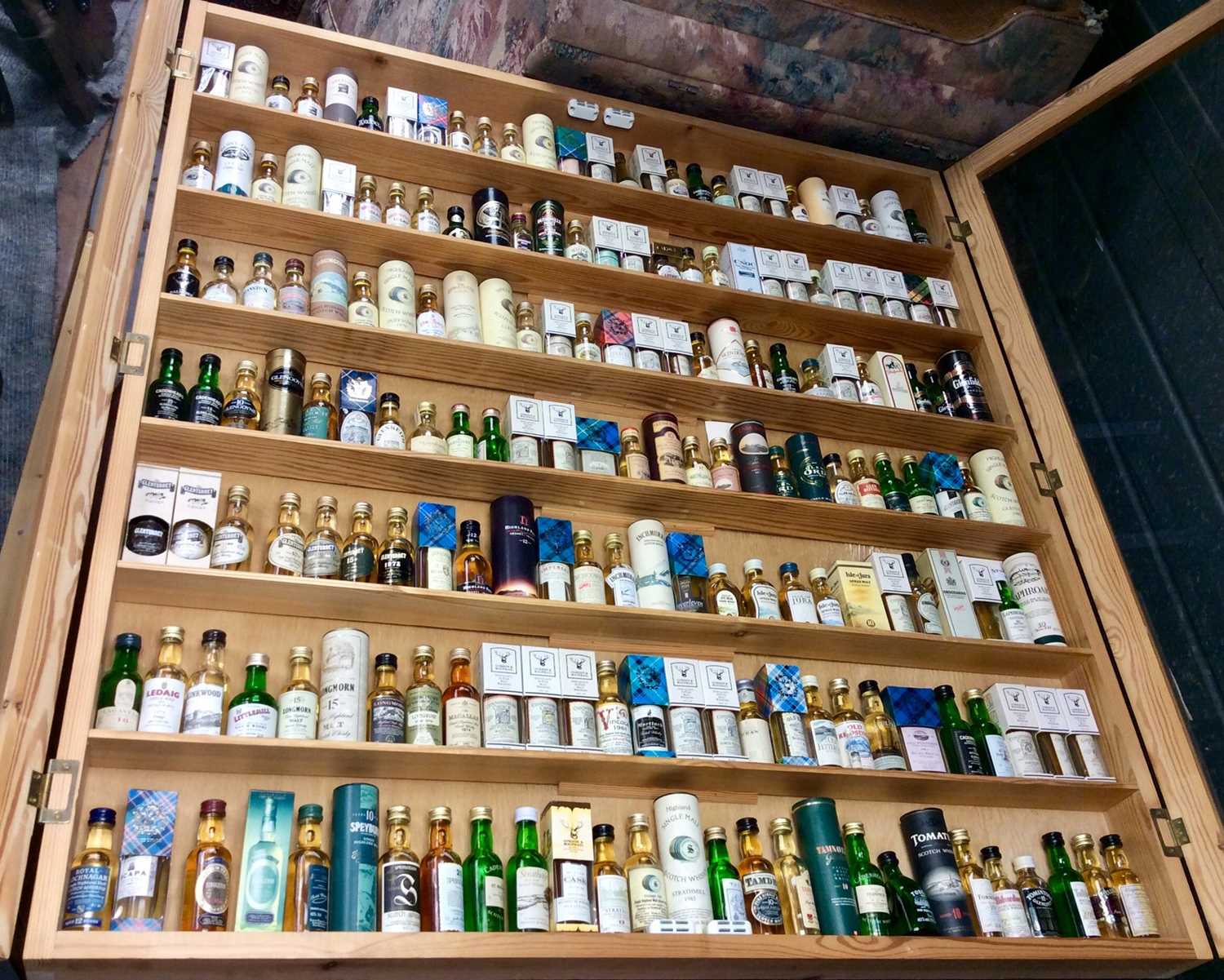 Fine collection of Scottish single malt whiskies in display cabinet, believed to represent all but t