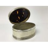 George V silver jewellery box of oval form, the hinged lid with inset tortoiseshell panel enclosing