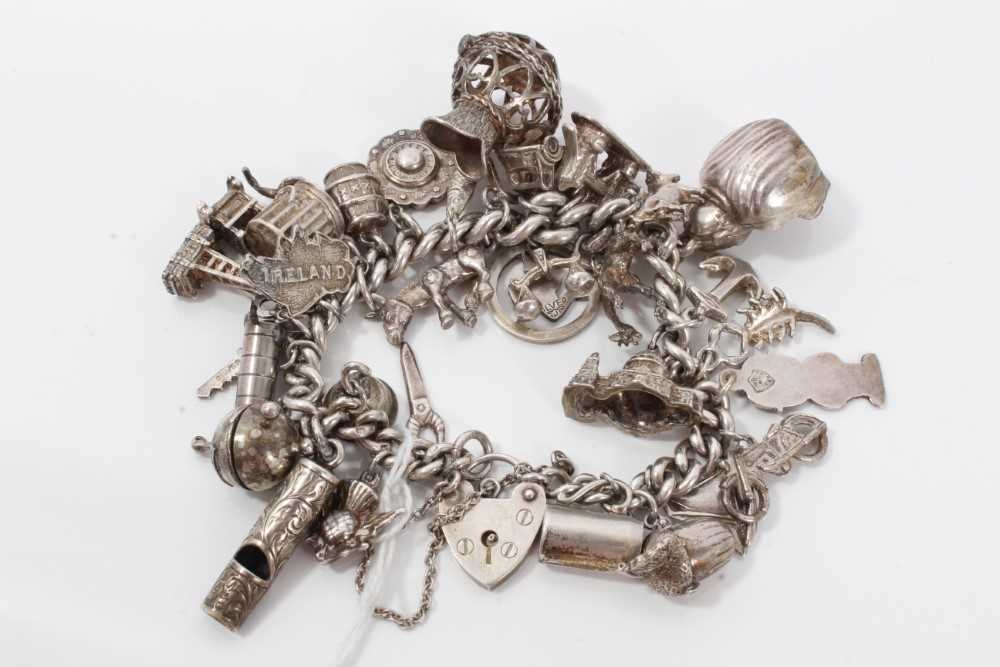 Silver charm bracelet with a collection of silver and white metal charm and padlock clasp.