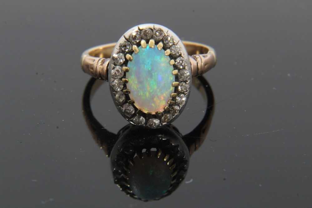 Antique opal and diamond cluster ring with an oval cabochon opal surrounded by nineteen old cut diam