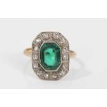 1920s diamond and green stone cocktail ring with a step cut green stone surrounded by a border of ol