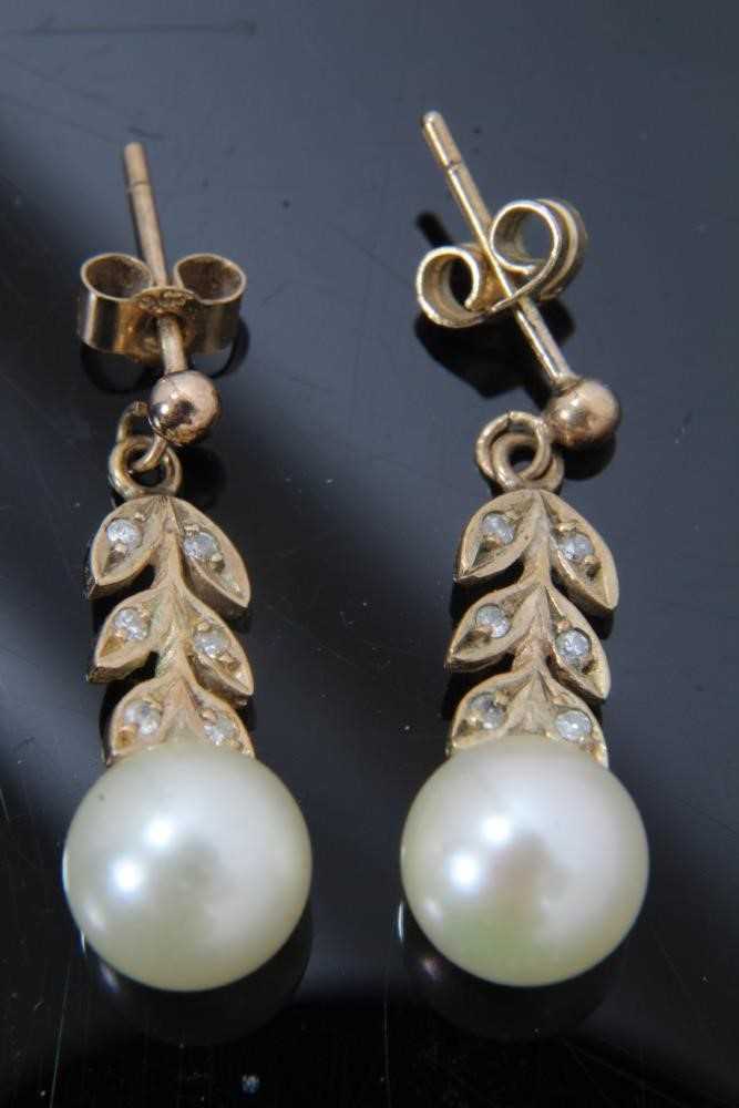 Pair of cultured pearl and diamond pendant earrings with a 7mm cultured pearl suspended from stylize