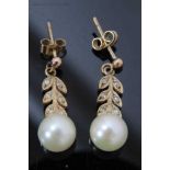 Pair of cultured pearl and diamond pendant earrings with a 7mm cultured pearl suspended from stylize