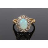 Opal and diamond cluster ring with an oval cabochon opal measuring approximately 8.9mm x 6.4mm x 2.1