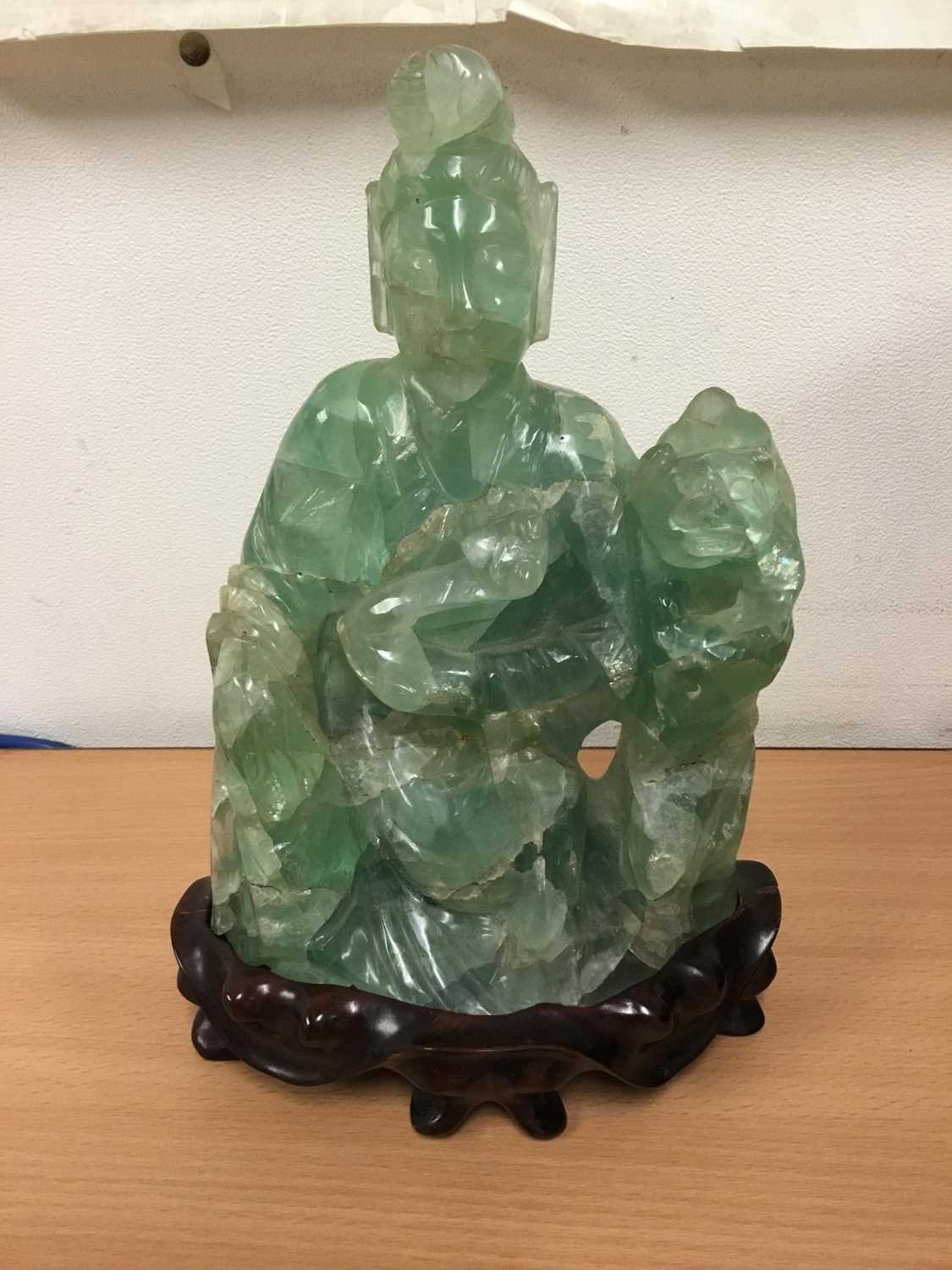 Oriental carved hardstone sculpture of a seated figure and dog of Fo, on carved hardwood base, 24cm