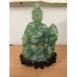 Oriental carved hardstone sculpture of a seated figure and dog of Fo, on carved hardwood base, 24cm