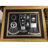 Selection of Arabic metal jewellery in frame and tapestry