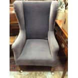 Antique wing back armchair upholstered in blue material on turned mahogany legs with ceramic castors