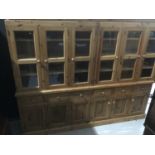 Large pine bookcase/dresser in four sections with glazed doors above, drawers and cupboards below