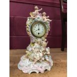 Decorative china mantel clock with courting couple and cherubs and enamelled dial