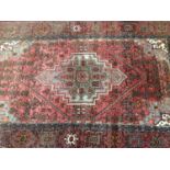 Eastern rug with geometric decoration on red ground. 207cm x 127cm
